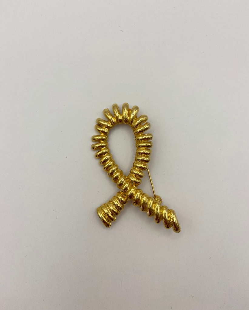 Broche en forma de bucle con diseño retorcido en tono dorado